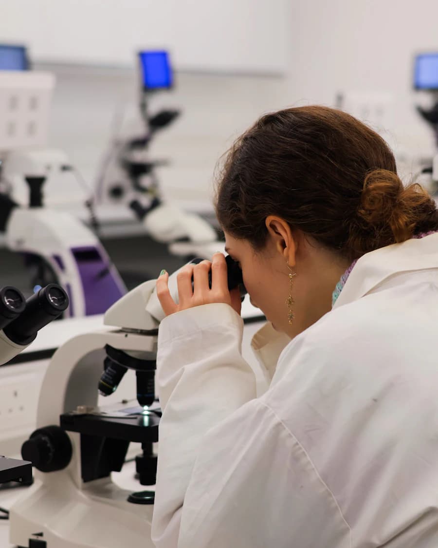Scientist in a lab coat looking into a microscope