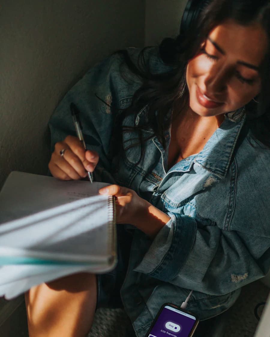 Woman in a denim jacket writing notes in a notebook