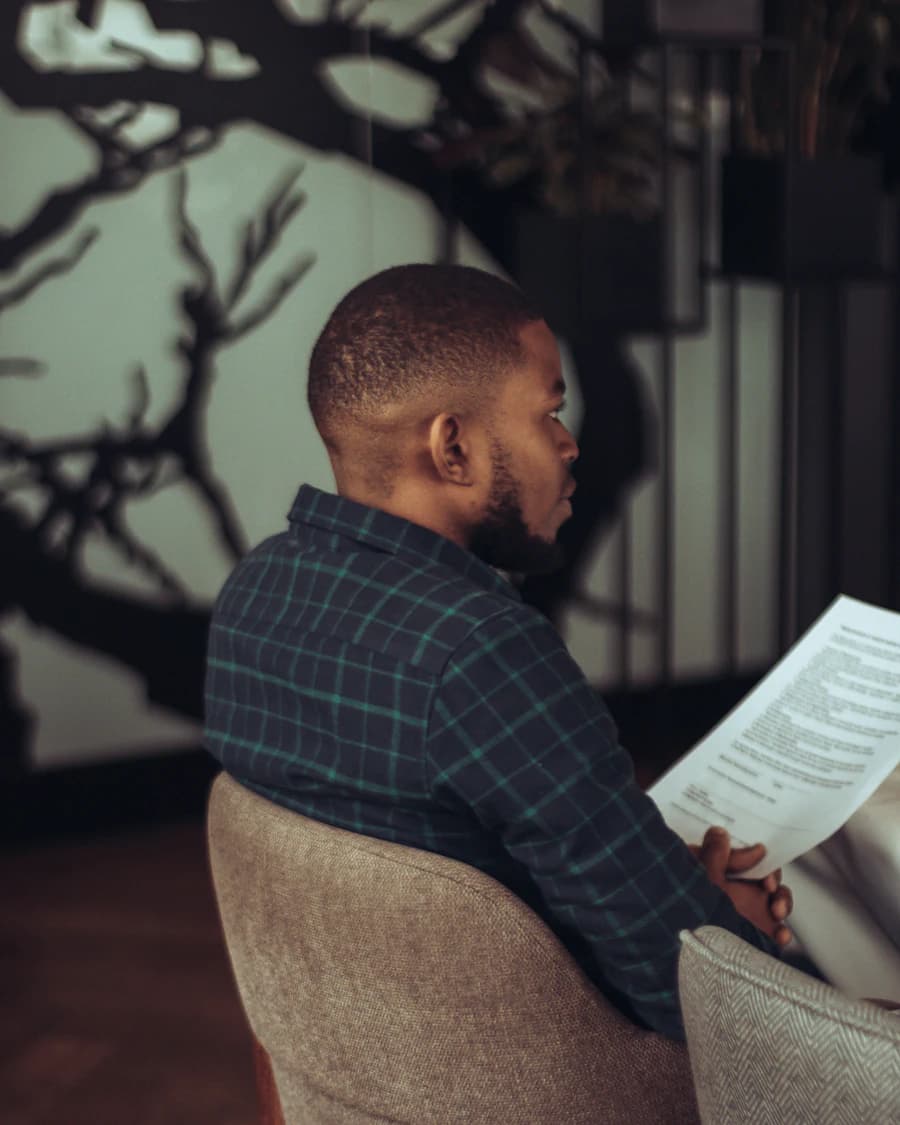 Man in a plaid shirt reading a document in an armchair